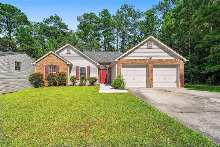Brick and siding exterior with a two-car garage, red front door, and a concrete driveway