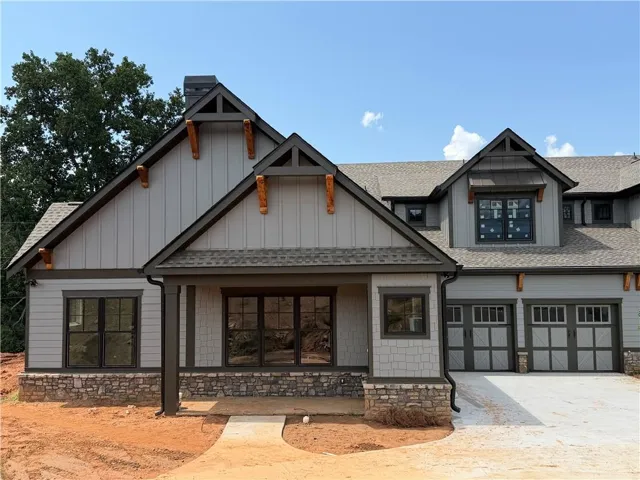 Craftsman-style exterior featuring a stone foundation, board and batten siding, and architectural shingles