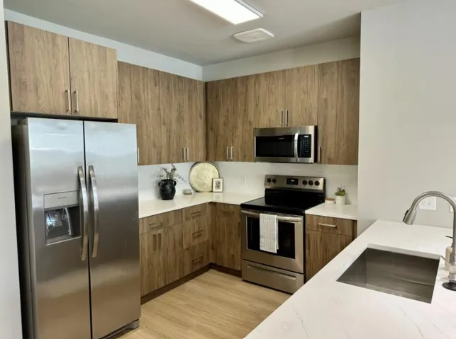 Kitchen featuring appliances with stainless steel finishes, sink, light stone counters, and light hardwood / wood-style flooring