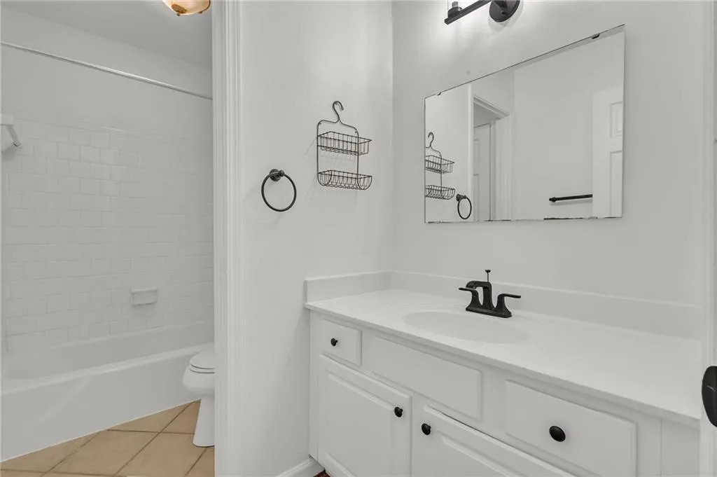 Full bath featuring vanity, light tile patterned flooring, and shower / bath combination