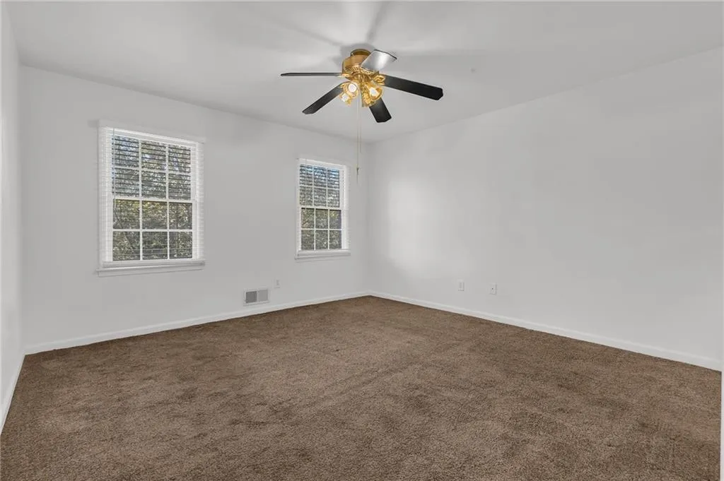 Empty room with dark carpet and a ceiling fan