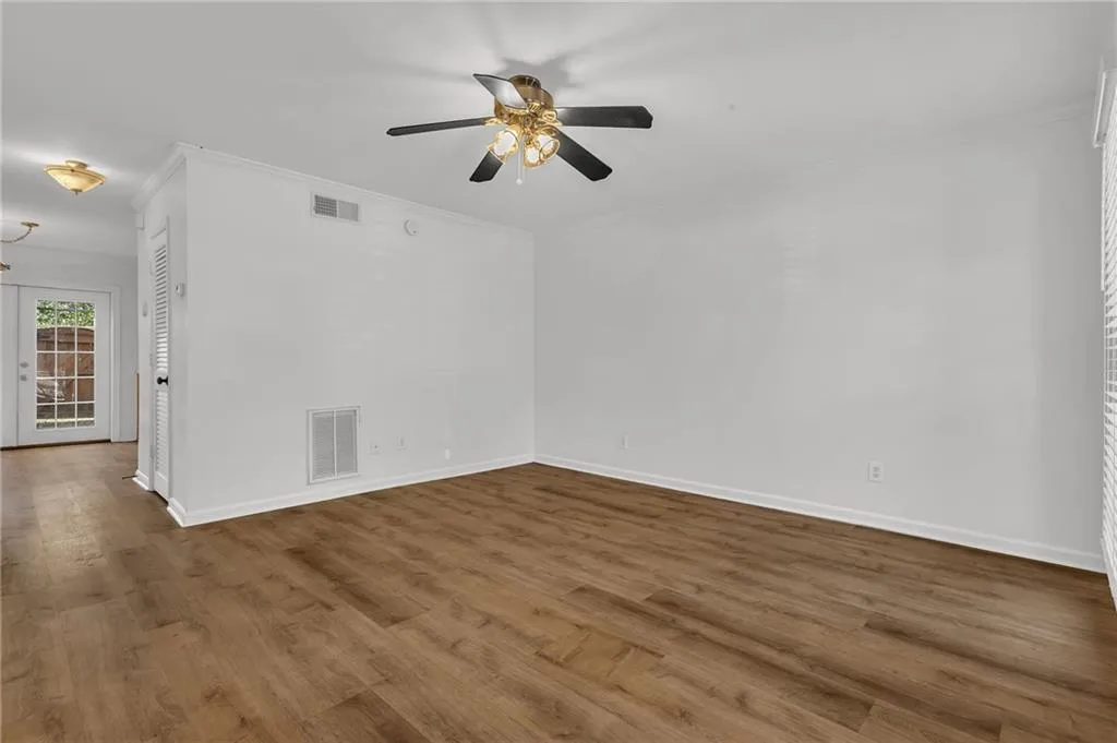 Empty room with wood finished floors, crown molding, and a ceiling fan