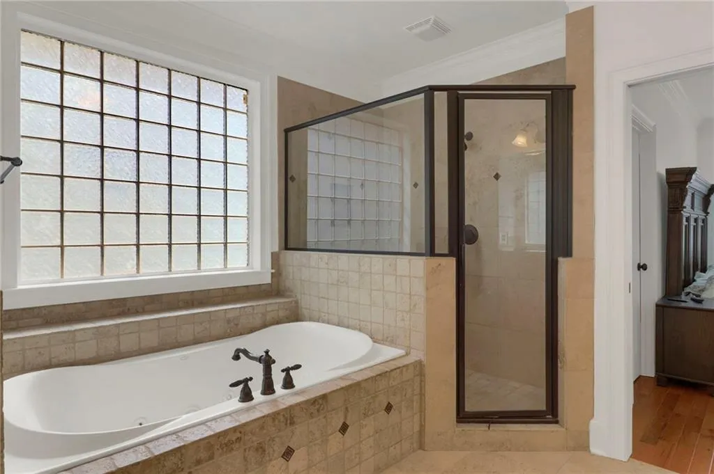Full bath featuring a tub with jets, a stall shower, and crown molding
