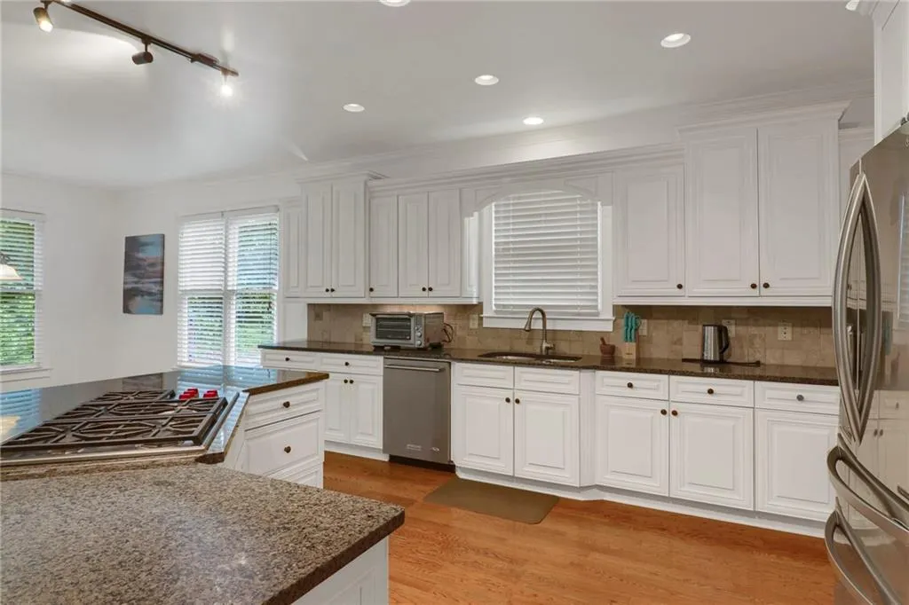 Kitchen featuring light wood-style floors, decorative backsplash, white cabinetry, stainless steel appliances, and ornamental molding
