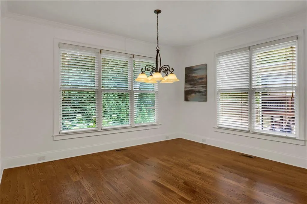 Unfurnished dining area with a chandelier, wood finished floors, and ornamental molding