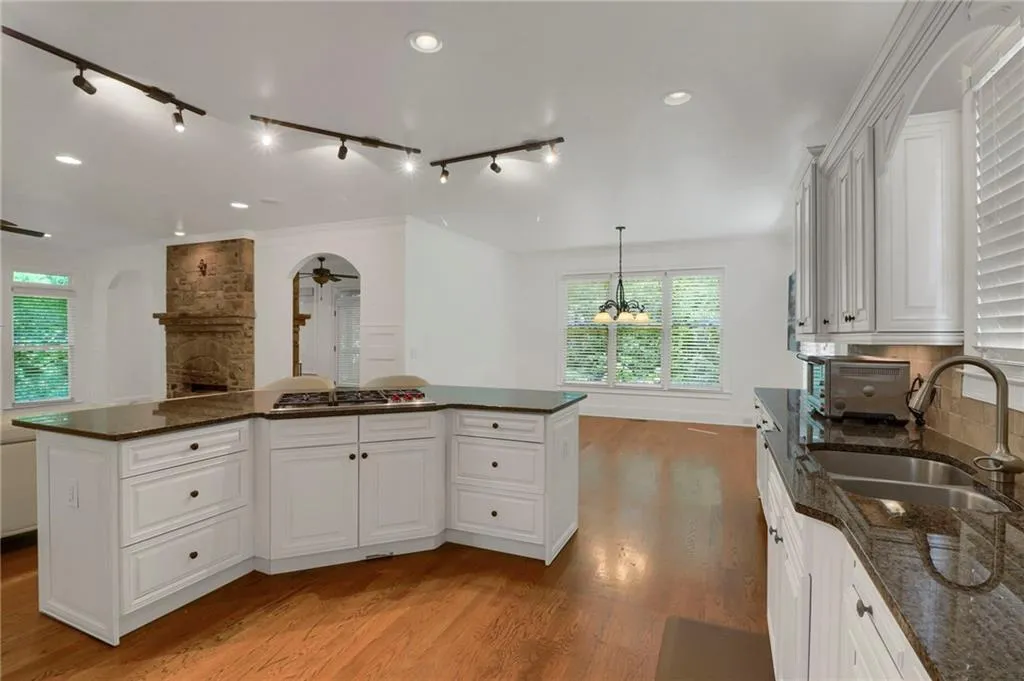 Kitchen featuring rail lighting, light wood-style floors, white cabinets, dark stone counters, and ornamental molding