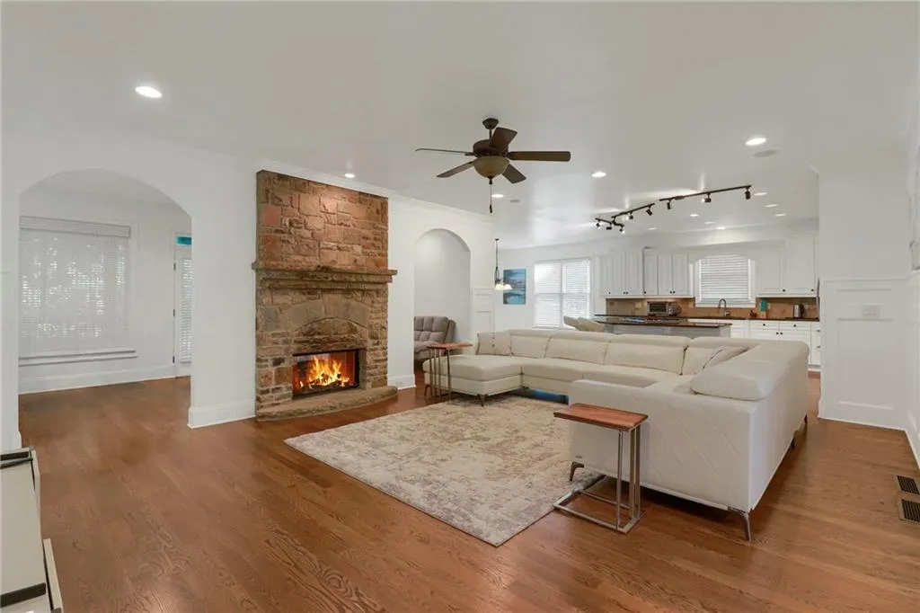 Living area with a fireplace, arched walkways, wood finished floors, crown molding, and rail lighting
