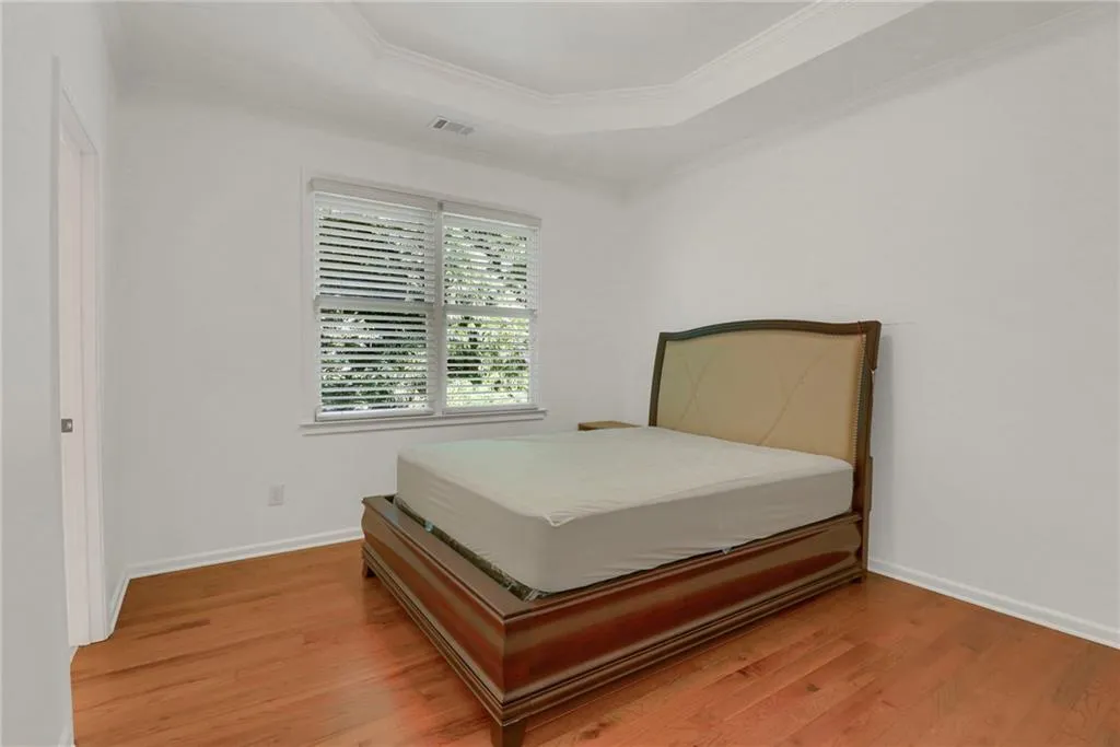 Bedroom with crown molding, light wood-style floors, and a tray ceiling