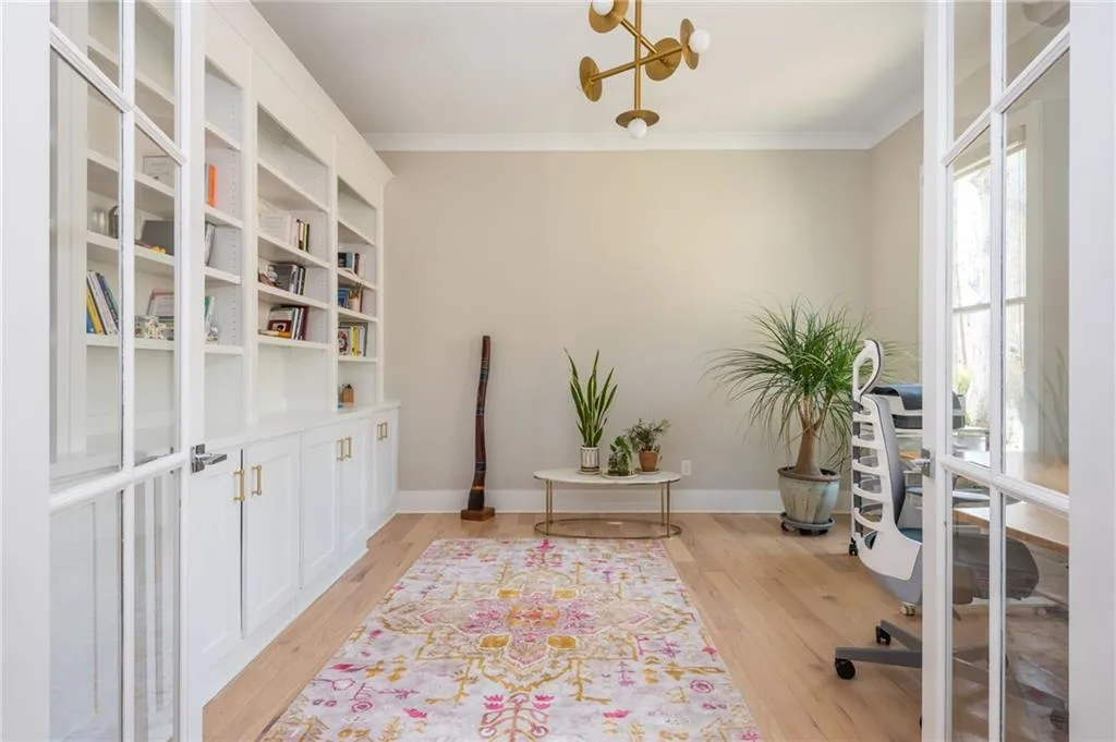 Office featuring crown molding, light wood-style flooring, a notable chandelier, and baseboards
