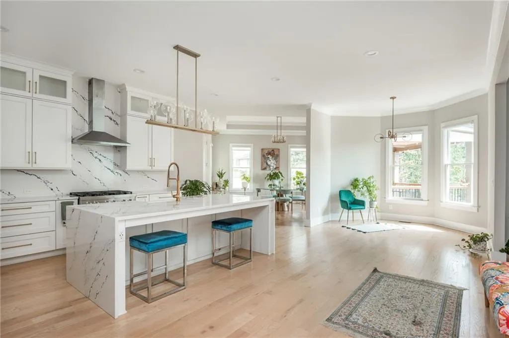 Kitchen featuring light wood finished floors, tasteful backsplash, a healthy amount of sunlight, and wall chimney range hood