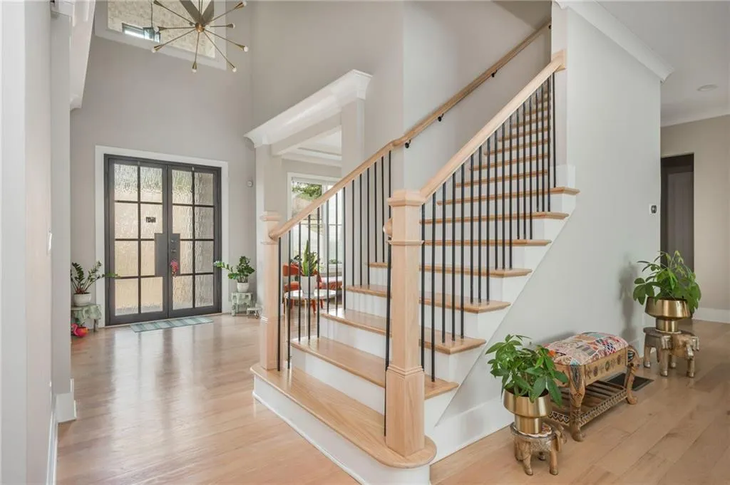 Stairs featuring a high ceiling, an inviting chandelier, wood finished floors, and ornamental molding