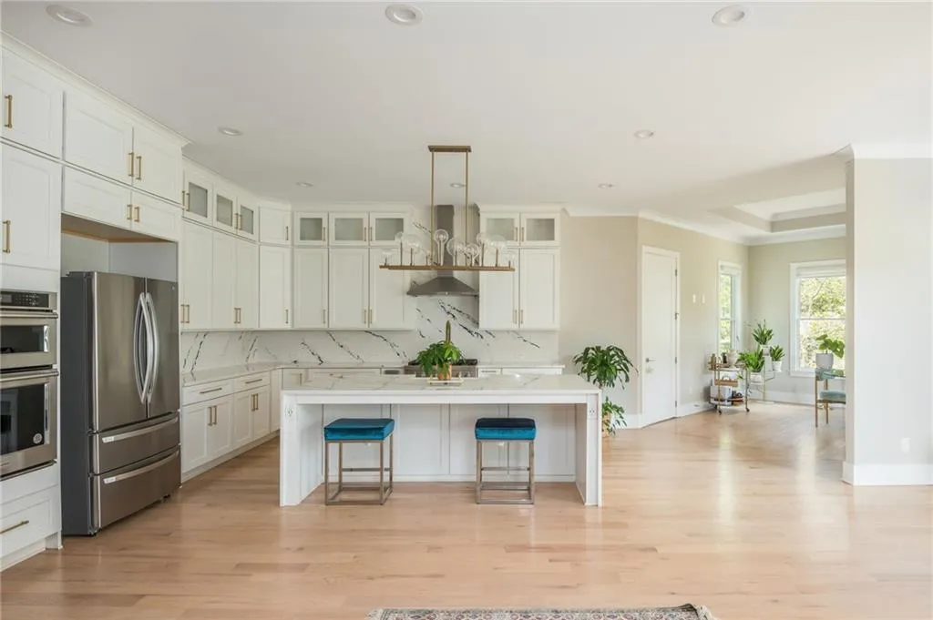 Kitchen with a breakfast bar area, an island with sink, light countertops, appliances with stainless steel finishes, and tasteful backsplash