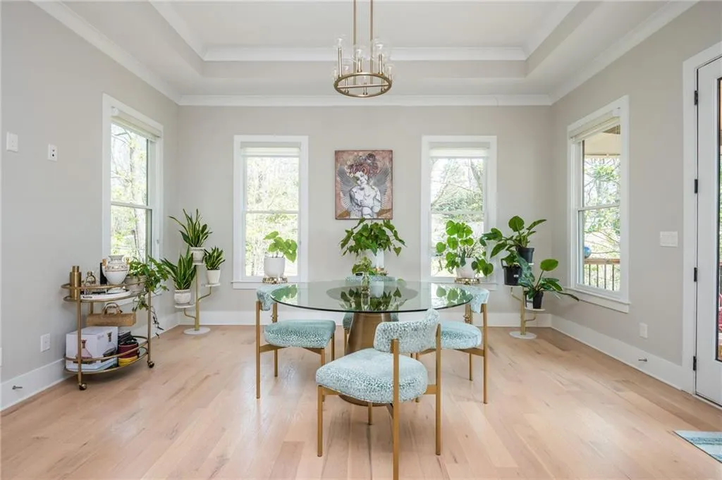 Dining room with a raised ceiling, a notable chandelier, and light wood-type flooring