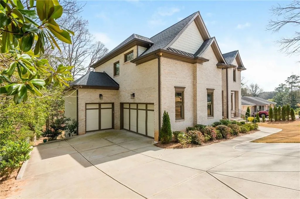 View of side of home with concrete driveway, 3 car garage, brick sides and a shingled roof