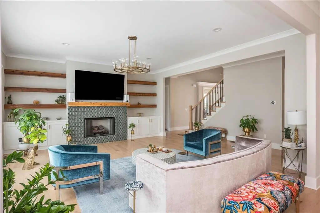 Living room featuring wood finished floors, an inviting chandelier, a tile fireplace, rustic mantle and shelves