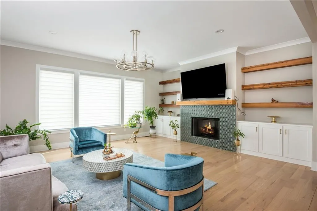 Living room featuring a tiled fireplace, ornamental molding, recessed lighting, an inviting chandelier, and wood finished floors