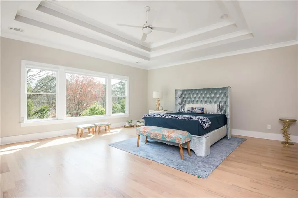 Primary Bedroom featuring a tray ceiling and multiple windows for great views all year around