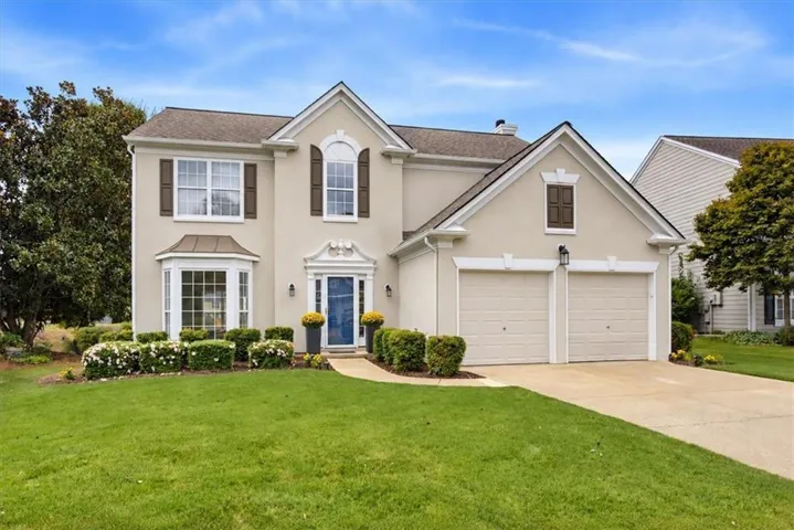 Stucco exterior with a two-car garage, bay window, and a gabled entry