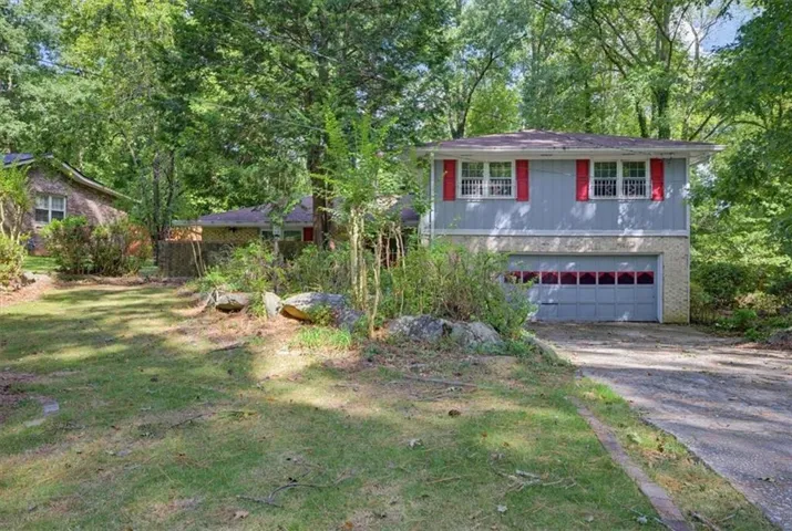 Split-level residence featuring a two-car garage, red window shutters, and a light blue exterior