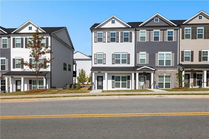 Contemporary townhome exterior featuring an integrated garage, covered entry, multiple windows with dark shutters, and a gabled roofline