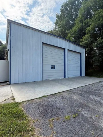 Freestanding light-colored metal structure featuring a peaked roofline and dark-colored trim