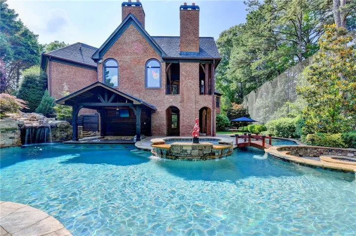 Spacious outdoor oasis featuring a large swimming pool, integrated spa, and an attached covered patio with a built-in television