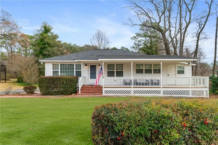Ranch-style home featuring covered porch, a front yard, and a shingled roof