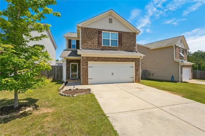 Brick and siding exterior featuring a covered entry, an attached garage, a concrete driveway, and a landscaped bed