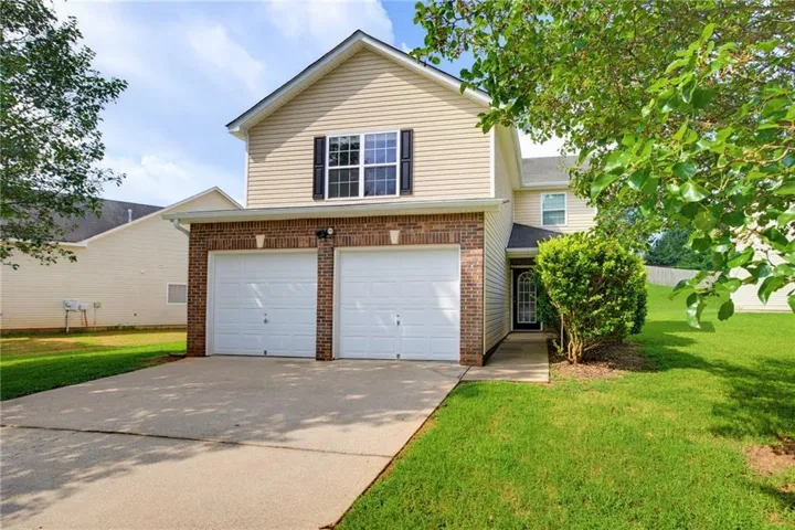 Exterior featuring brick and siding facade, two-car garage, concrete driveway, and covered front entry