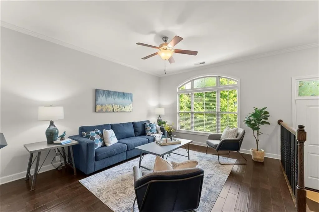 Living room featuring ornamental molding, dark hardwood / wood-style flooring, and ceiling fan