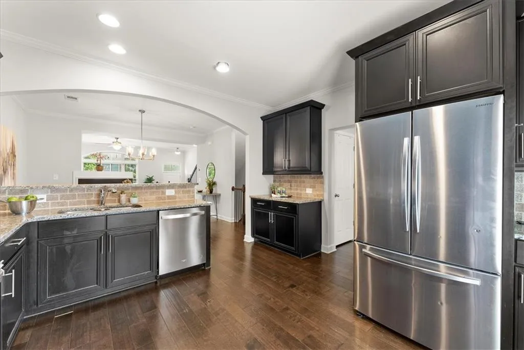 Kitchen with pendant lighting, sink, backsplash, appliances with stainless steel finishes, and dark hardwood / wood-style flooring