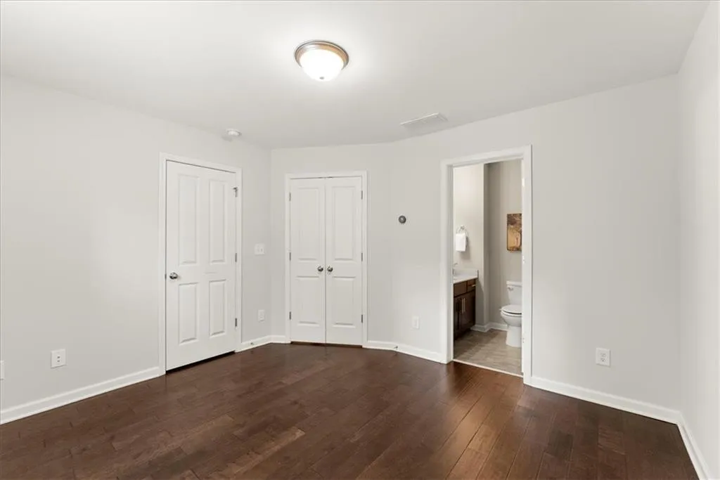 Unfurnished bedroom with hardwood / wood-style floors and ensuite bath