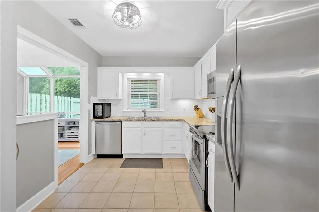 Kitchen featuring appliances with stainless steel finishes, a sink, and white cabinets