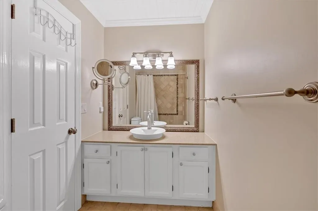 Full bathroom featuring vanity, tiled shower, and ornamental molding