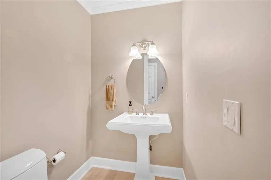 Half bath with baseboards, toilet, and crown molding