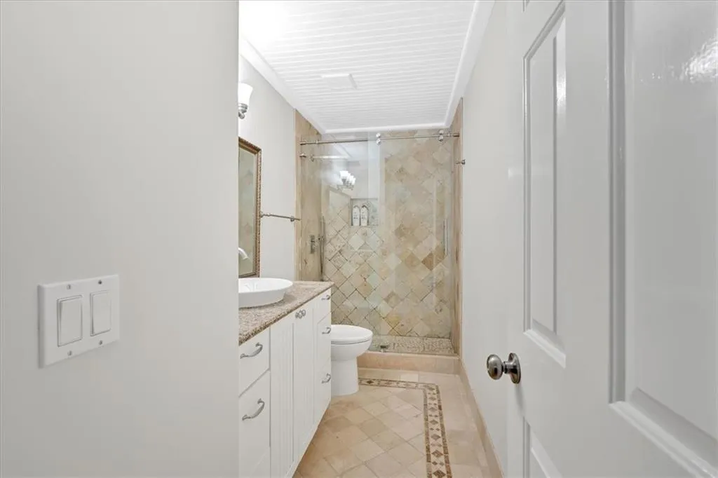 Bathroom with inlaid floor details, vanity, toilet, a stall shower, and tile patterned flooring
