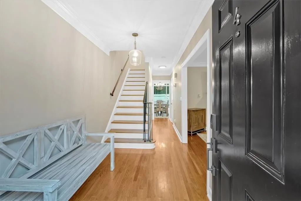 Foyer entrance featuring light wood-style floors, stairs, ornamental molding, and baseboards