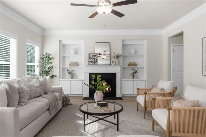 Living area featuring a central fireplace with a white mantel, flanked by built-in shelving and lower cabinetry