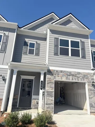 Attached single-car garage, stone veneer facade, gray horizontal siding, front porch with columns, and dark gray front door