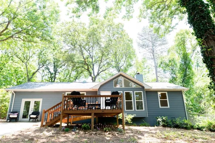 Exterior featuring a spacious wood deck, gray siding, and a gable architectural element