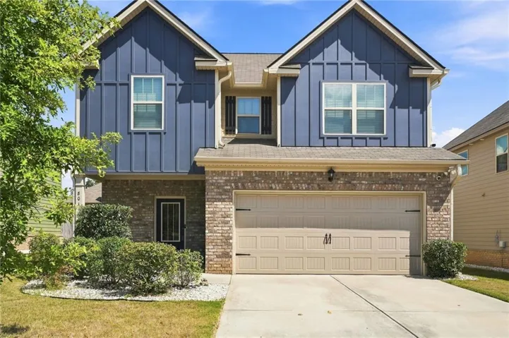 Two-story exterior featuring blue vertical siding, brick accents, a two-car garage, and a concrete driveway