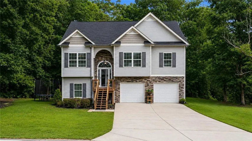 Two-story home with a light gray siding exterior, dark gray shutters, and a stone facade accent