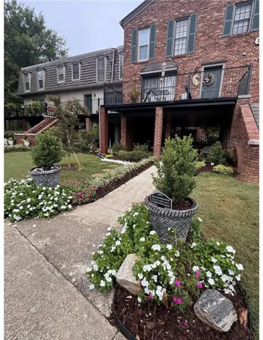 Brick exterior with green shutters, a second-story balcony with iron railings, and a lower-level covered patio