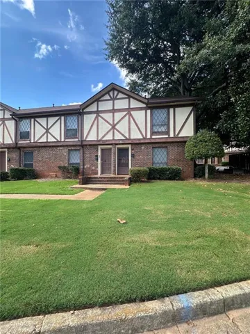 Tudor-style house featuring a front lawn and brick siding
