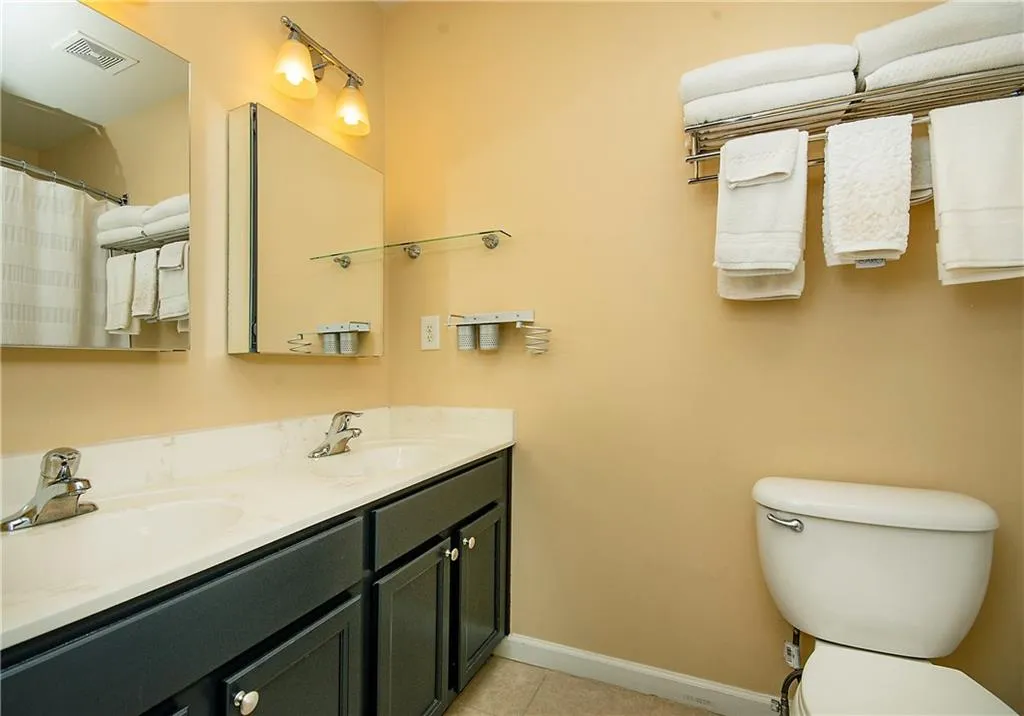 Full bath with double vanity, light tile patterned floors, and curtained shower