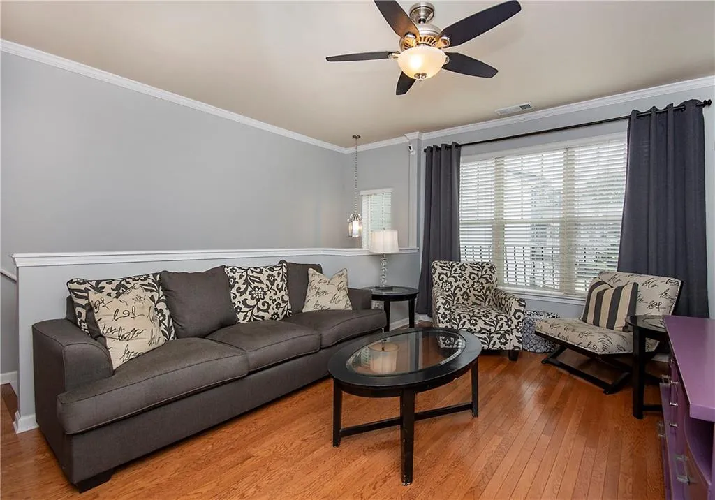 Living area with ornamental molding, wood finished floors, and a ceiling fan