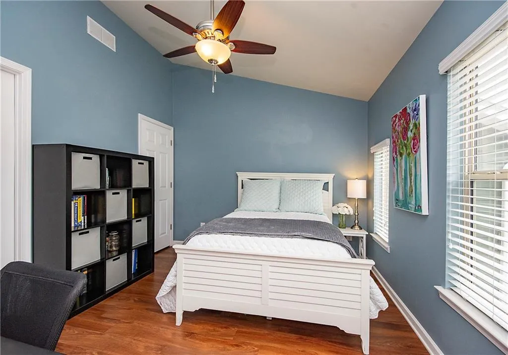 Bedroom with vaulted ceiling, wood finished floors, and ceiling fan