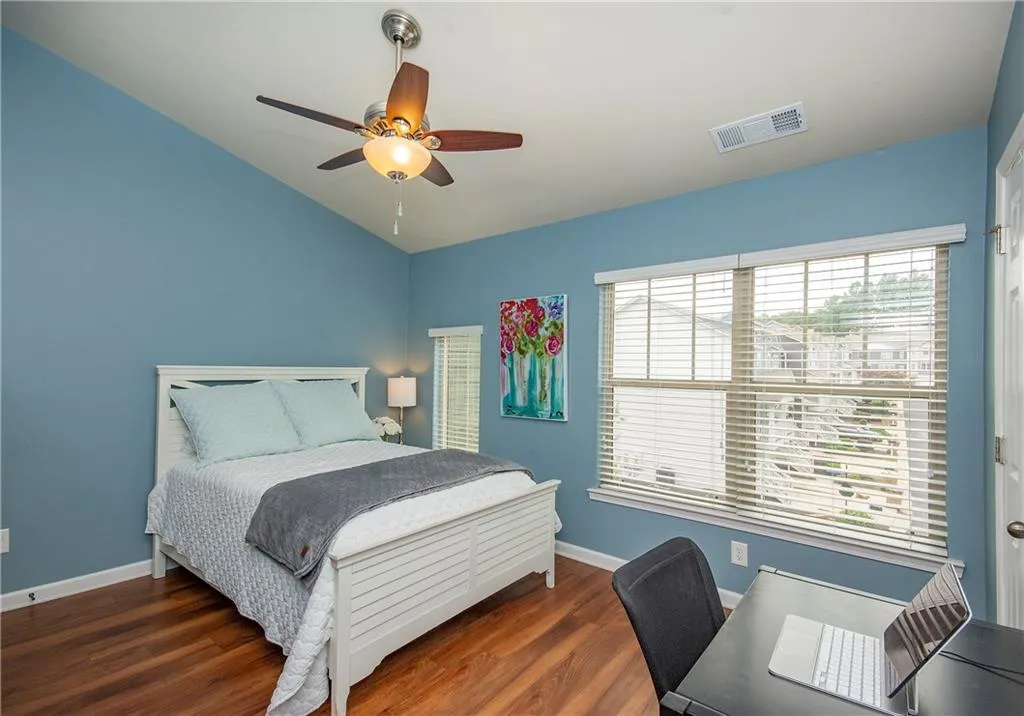 Bedroom with lofted ceiling, wood finished floors, ceiling fan, and a desk