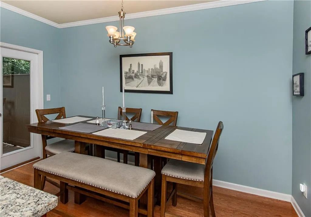Dining room with wood finished floors, ornamental molding, and a chandelier
