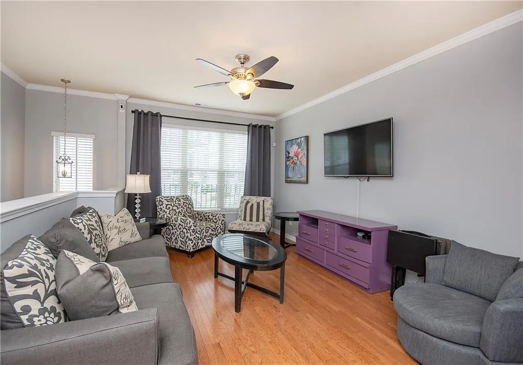 Living area featuring ornamental molding, light wood-type flooring, and a ceiling fan